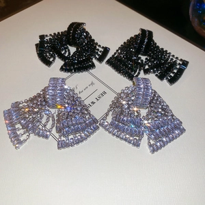 Macro shot of silver needle earrings with bowknot tassels and sparkling crystal zircons