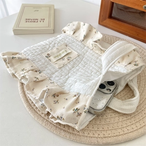 Detailed view of quilted cotton wrist bag with floral trim showing phone storage capacity