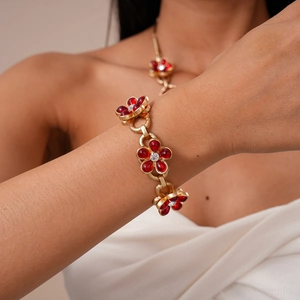 Detail of gold chain bracelet with red crystal flowers and inlaid sparkling diamonds