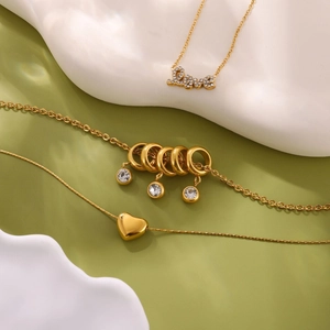 Vue macro de colliers en acier doré avec pendentifs cœur et Love sur décor moderne