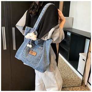 Detail of blue denim tote bag with leather label and cute white cloud charm decoration