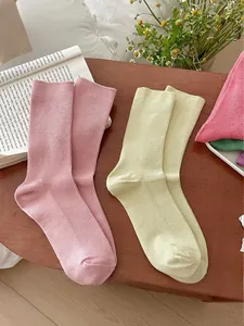 Detail of pink and beige cotton knit crew socks with vertical ribbed texture on wood