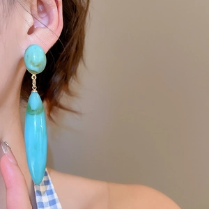 Detail of light blue marble drop earring worn by model with gold metal accents