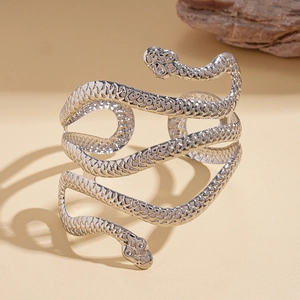 Close-up of silver snake-shaped cuff with detailed scales texture against a rock background