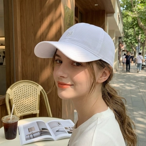 Breathable white baseball cap with shield embroidery worn by a model in outdoor setting