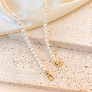 Macro detail of high-luster imitation pearls with golden metal clasps on silk texture