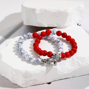 Detailed shot of couple's marble bead bracelets with silver magnetic heart pendants