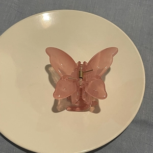 Detail shot of a translucent cherry pink butterfly hair claw clip with metal spring