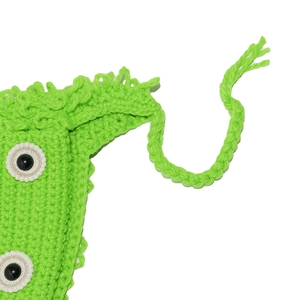 Macro view of neon green handmade crochet monster hat with knit texture and eye details