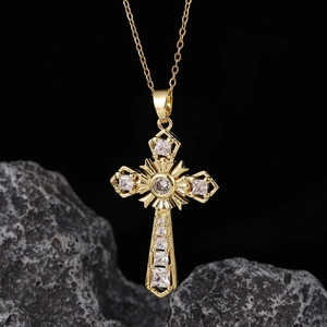 Dettaglio di una collana a croce d'oro con zirconi cubici su una pietra vulcanica