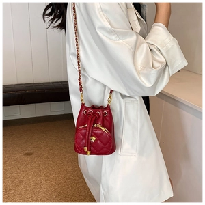 Detail of a red quilted bucket bag with golden chain strap and camellia flower pocket