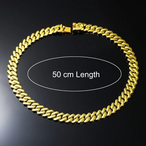 Close-up of 50 cm length gold Cuban chain necklace on a black reflective surface