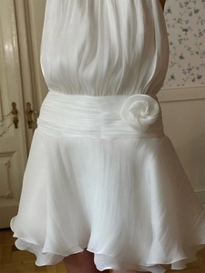 Detail of white halter dress featuring a pleated waist and 3D fabric rose decoration
