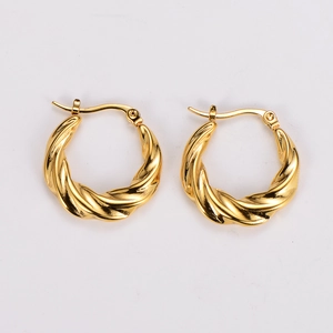Macro shot of gold twisted hoop earrings showing retro metal braided texture and finish