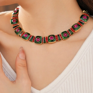 Close-up of vintage square pendant necklace with green enamel and red gemstone on neck