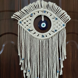 Detailed view of handmade macrame wall hanging with blue evil eye beads and tassels