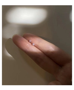 Macro shot of minimalist s999 silver stud earrings with pink zircon in four-prong setting