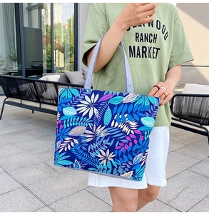 Detailed close-up of blue floral canvas tote bag with intricate leaf patterns and grey handles