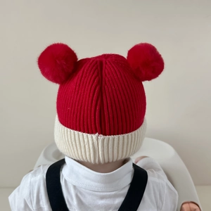 Warm knitted baby winter hat with red and white stitching and cute dual pom-poms