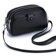 Detail of black pebbled leather crossbody bag featuring multiple zipper compartments