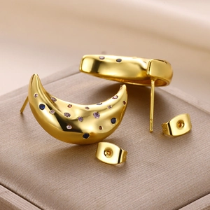 Macro shot of gold crescent moon stud earrings with colorful zircon in a gift box