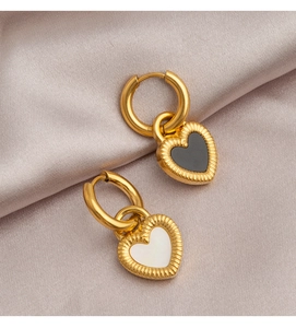 Detail of gold heart earrings with black and white mother of pearl inlay on silk fabric