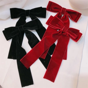 Close-up of elegant velvet bow hair clips with long ribbons in red and black colors