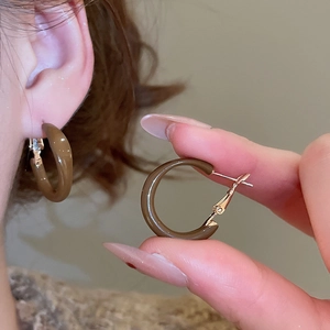 Detail of vintage brown C-shaped hoop earrings with gold metal clasp on a model