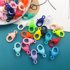 Close-up of colorful heart-shaped acrylic lobster clasps scattered on a teal background