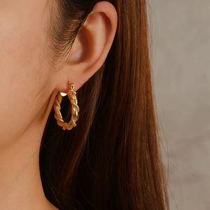 Twisted gold hoop earrings in 18k plated stainless steel worn by a model