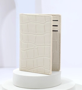 Close-up of cream crocodile pattern card holder with multiple slots on a white pedestal