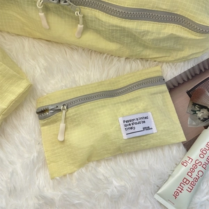 Close-up of a pale yellow checkered waterproof travel makeup bag with a zipper
