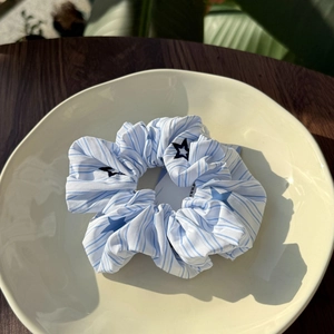 Close-up of blue and white striped scrunchie with star patterns on a wooden surface