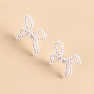 Close-up of handmade faux pearl bow earrings featuring elegant white beaded texture