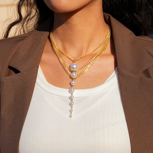Close-up of multilayered gold chain necklace with cascading white pearl tassels on a model