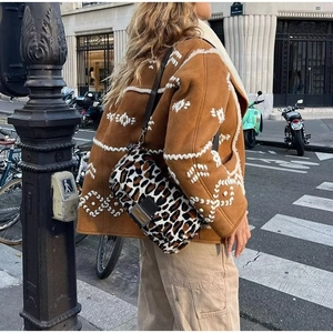 Street style shot of a leopard print shoulder bag with black leather strap detail