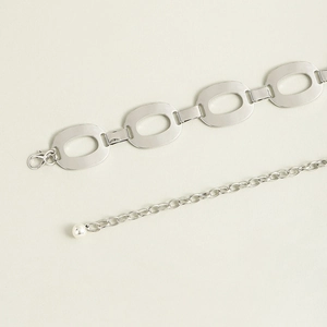 Close-up of silver metal chain belt with flat oval links and a small ball pendant