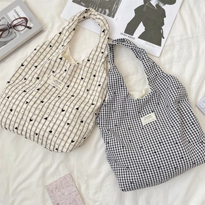 Detailed flat lay of canvas tote bags with plaid heart patterns and casual accessories