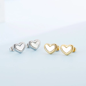 Close-up of gold and silver heart earrings with white mother of pearl inlay detail