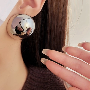Close-up of a model wearing a large high-polish silver spherical stud earring