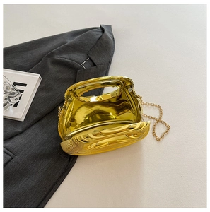 Flat lay of metallic gold evening clutch bag with chain strap on modern textured background