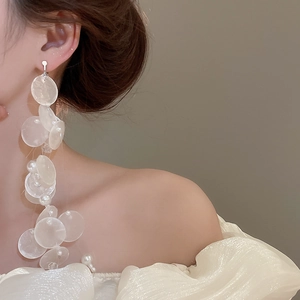 Close-up of elegant long pearl and shell tassel earrings on model for a refined look