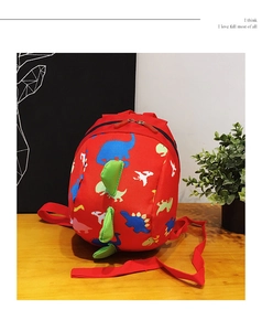 Detailed view of red kids backpack with 3D green dinosaur spikes on wood table