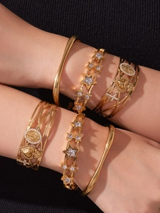 Vue détaillée de bracelets dorés superposés avec motifs d'étoile, cœur et croix
