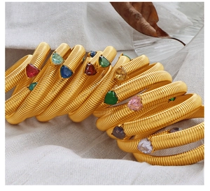 Detail of gold snake bone spring bracelets with heart shaped colorful gemstones