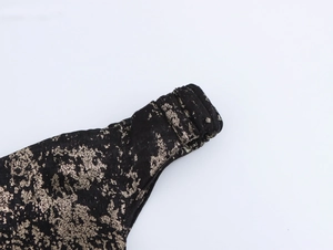 Detail shot of black fabric with gold foil texture and precise stitching on the shoulder strap