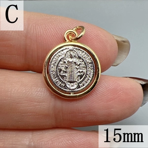 Macro view of a 15mm rotating Saint Benedict cross pendant with gold and silver finish
