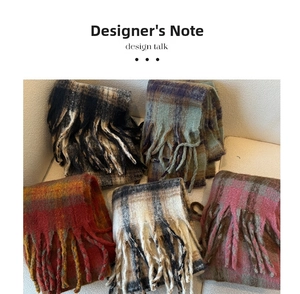 Detail showing five thick checkered scarves with tassels on a soft sofa surface