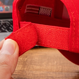Detailed close-up showing the adjustable red Velcro strap and fabric texture of the cap