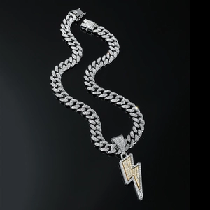 Close-up of hip hop silver Cuban chain with iced out lightning pendant on dark background